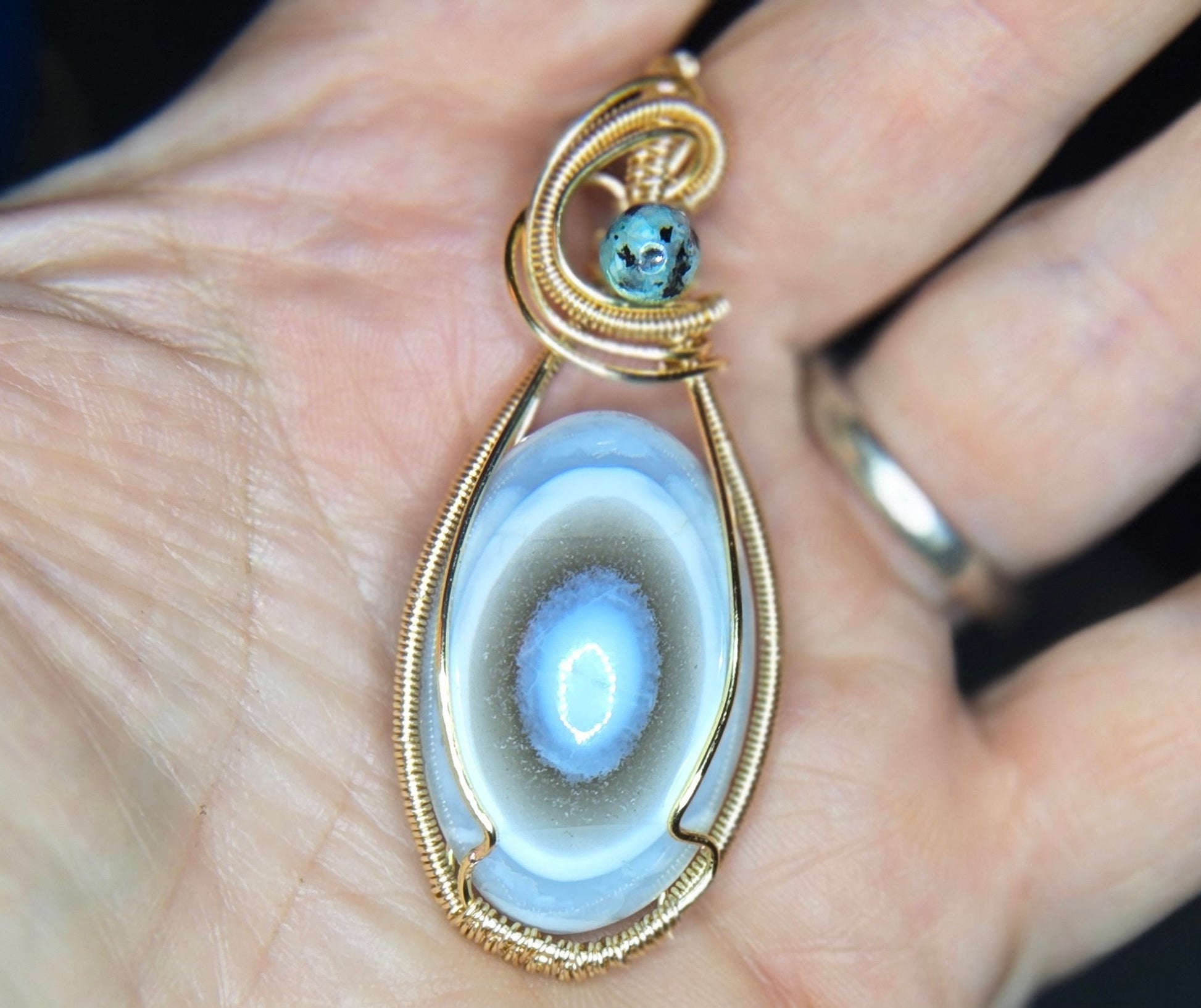 "Stillwater" – Blue Owyhee Opal Eye Pendant in Gold Wire Wrap with Teal Bead Accent